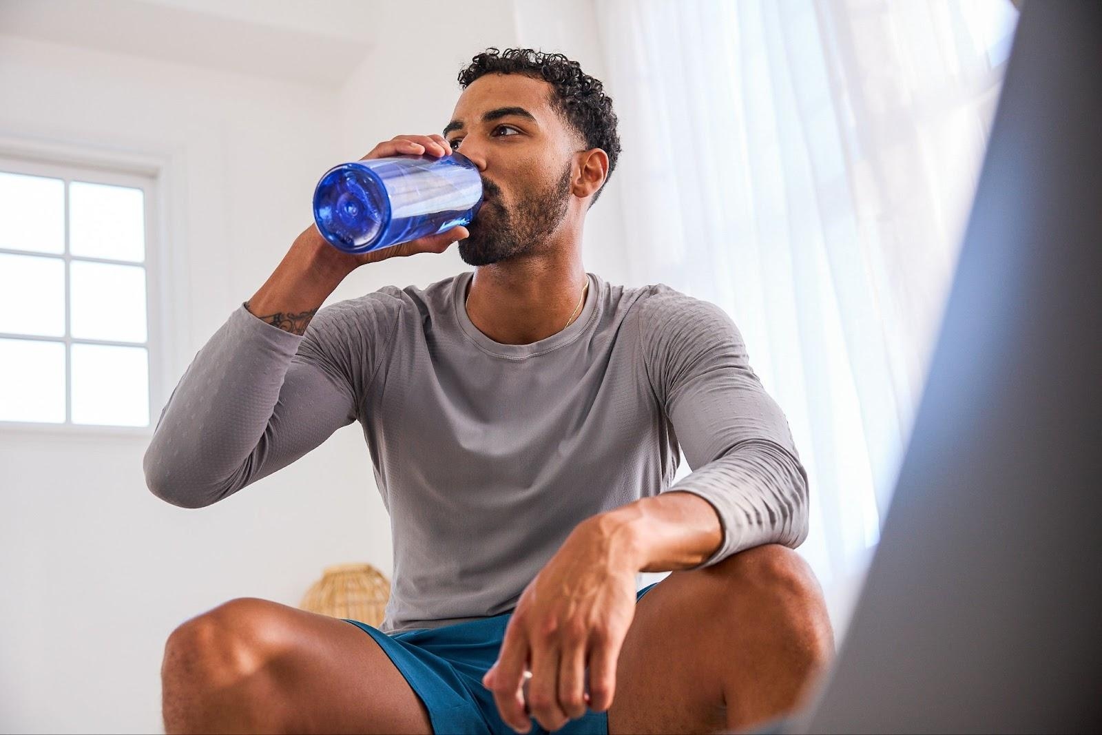 Man drinks water after exercising to help combat muscle soreness.