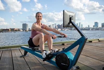 Woman does rowing drills on her indoor rowing machine.