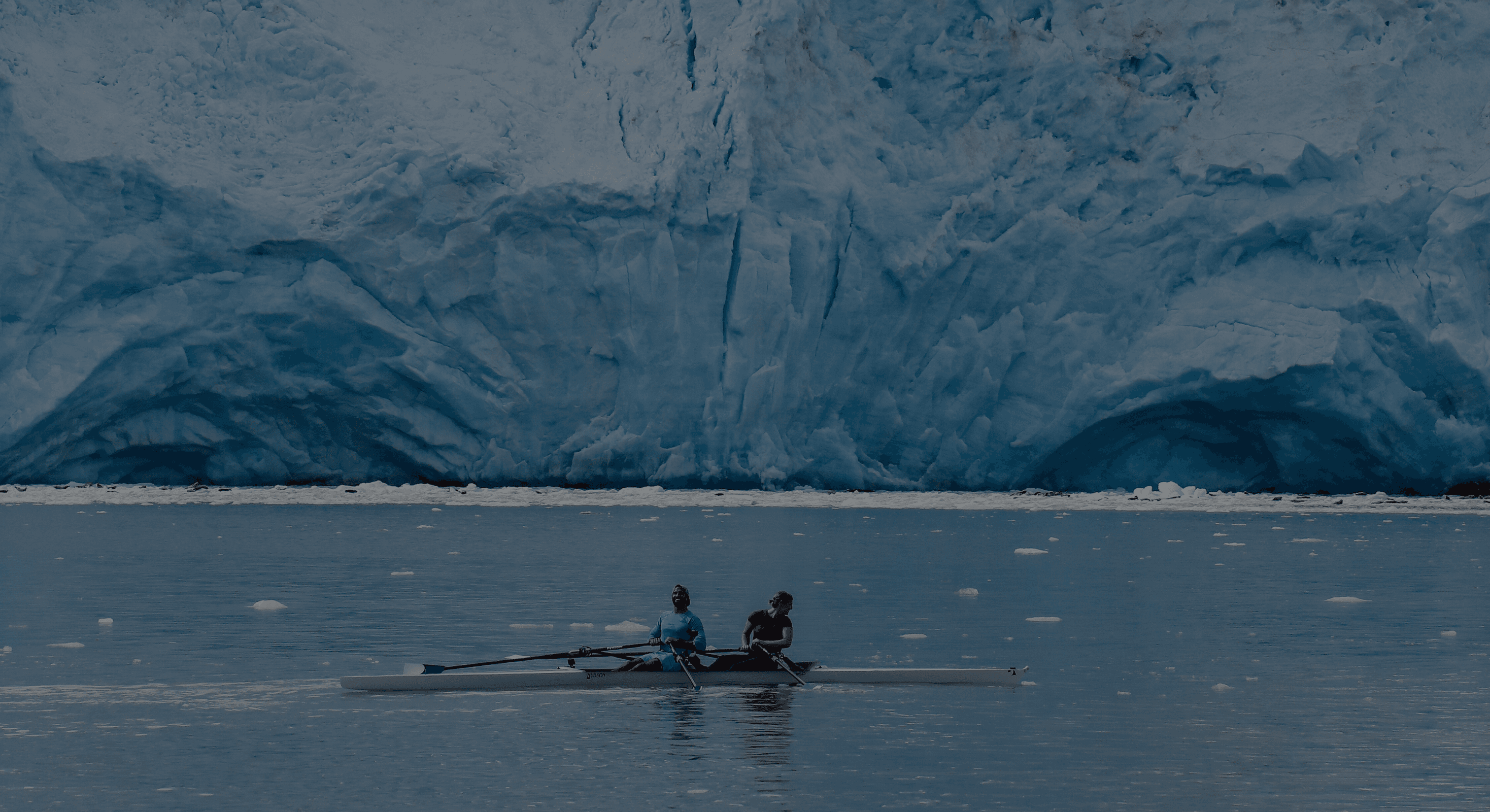 Epic shot of 2 coaches rowing in front of a glacier