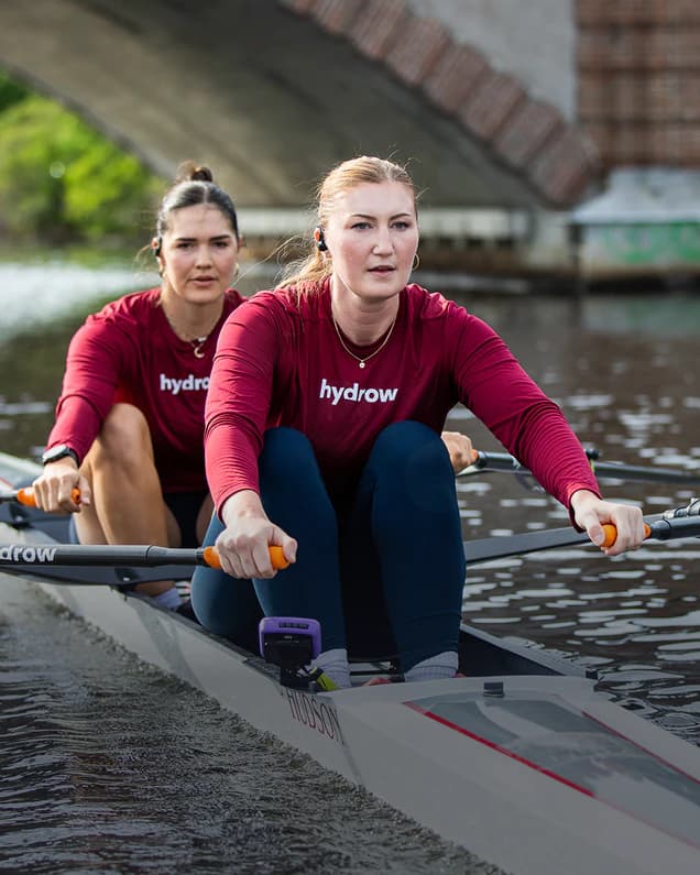 Two Hydrow athletes rowing side by side on the water