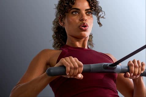 woman pulling rowing handle into chest