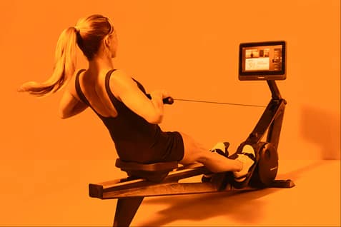 woman finishing a stroke on the Hydrow Rower in a bright, modern room