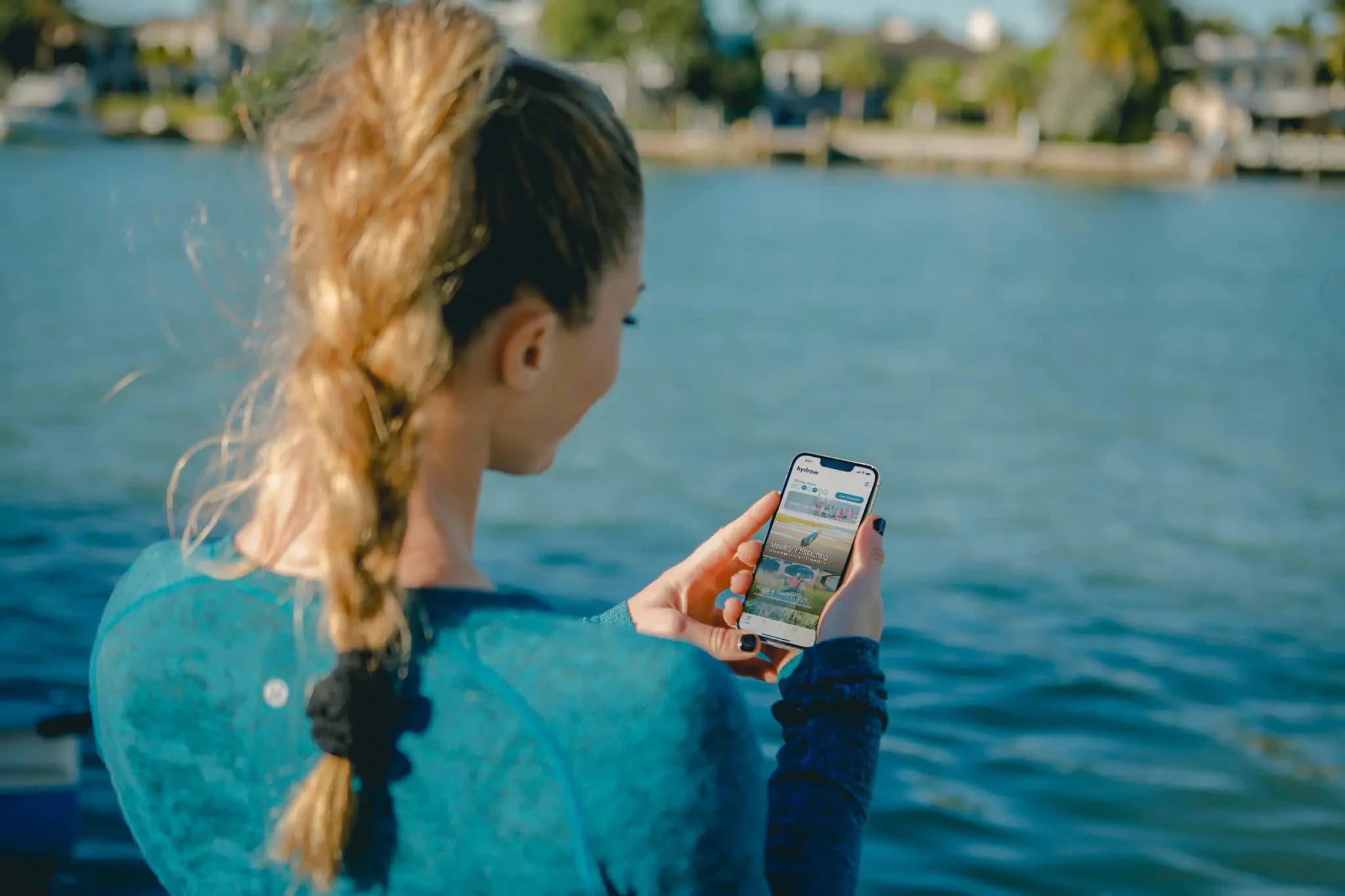 Woman by the water using the Hydrow app on her phone