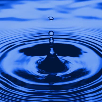 Water droplet creating ripples on blue water