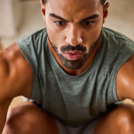 Man in a gray tank top focused mid-workout