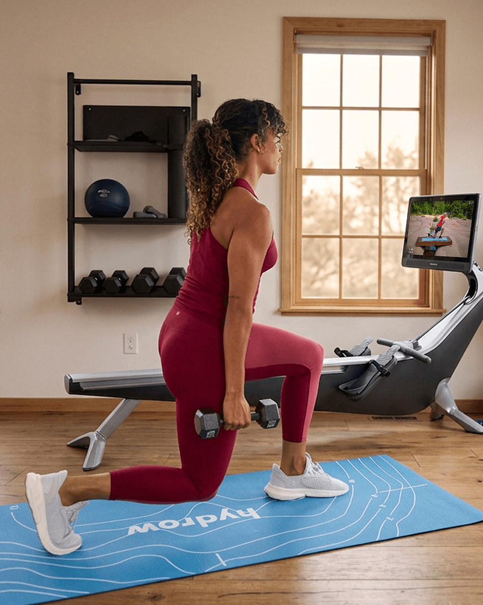 A Hydrow member cross-training with weights beside the rower