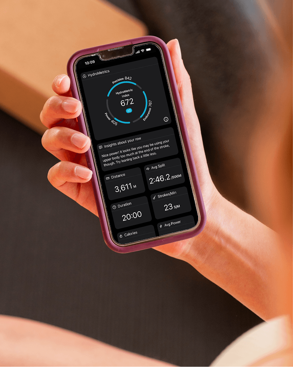 A person holding a phone displaying HydroMetrics performance data in the Hydrow app