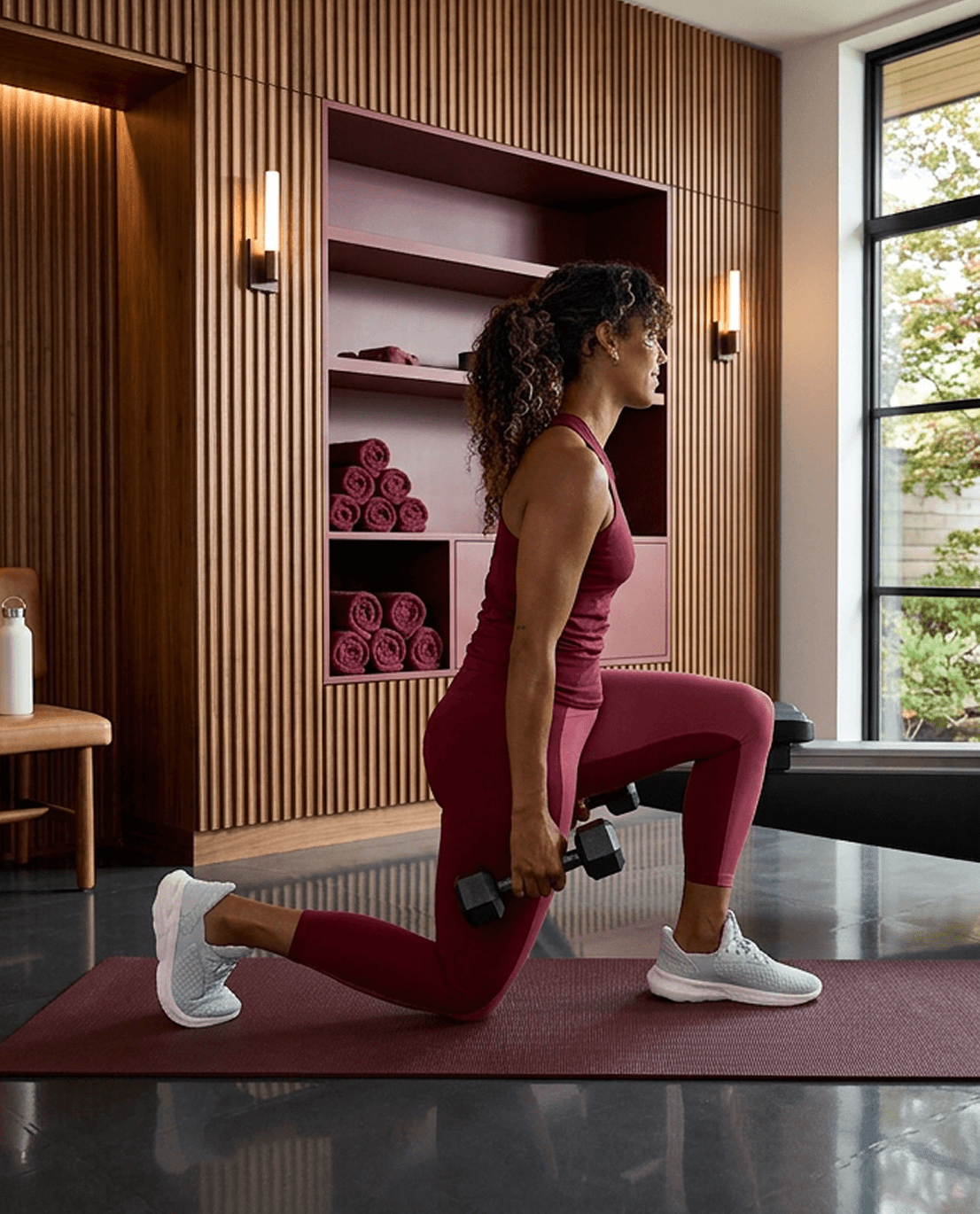 A person doing weighted lunges on a mat during a cross-training workout at home