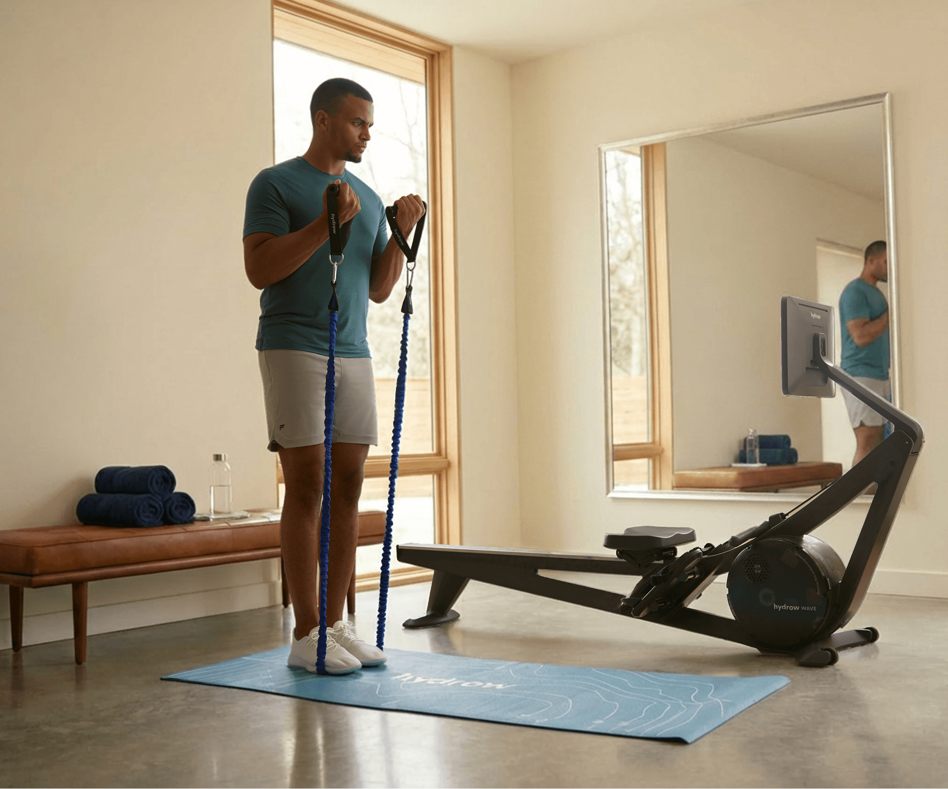 Man using exercise bands for an on-the-mat workout alongside Hydrow Wave Rower