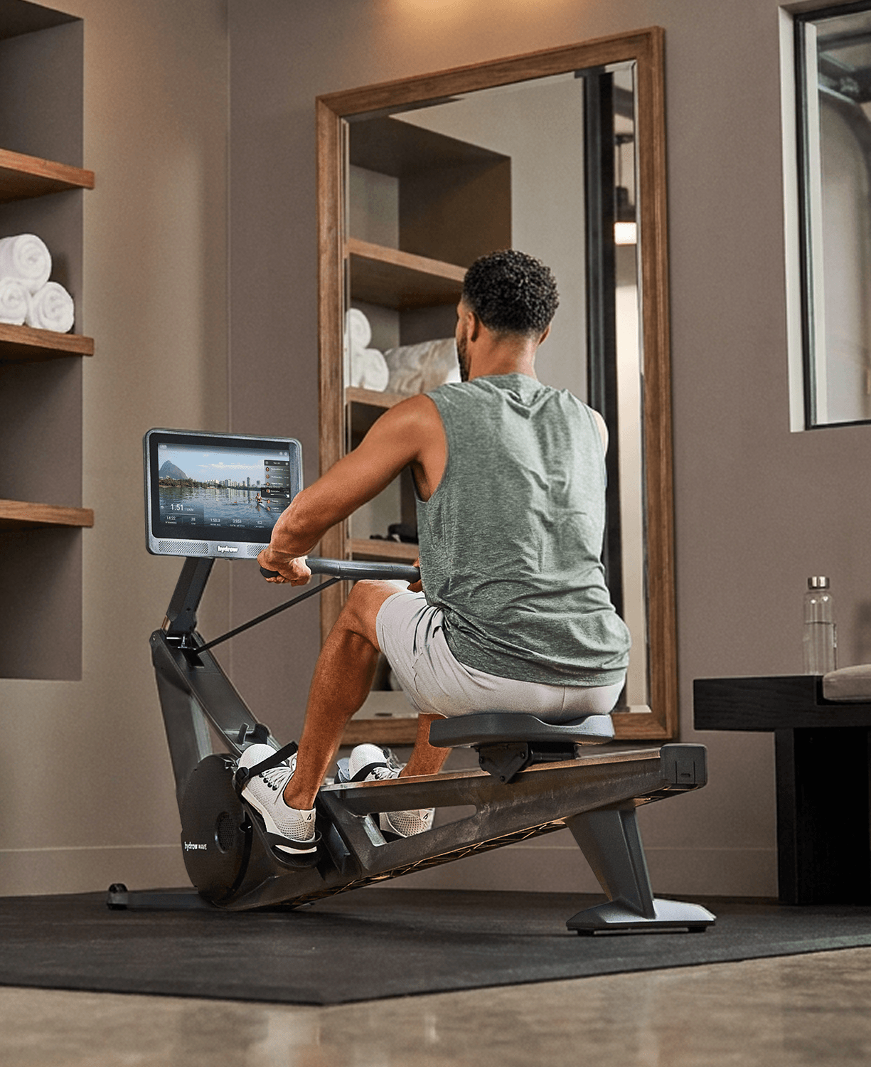 Back view of a person rowing on the Hydrow Wave rower in front of a mirror