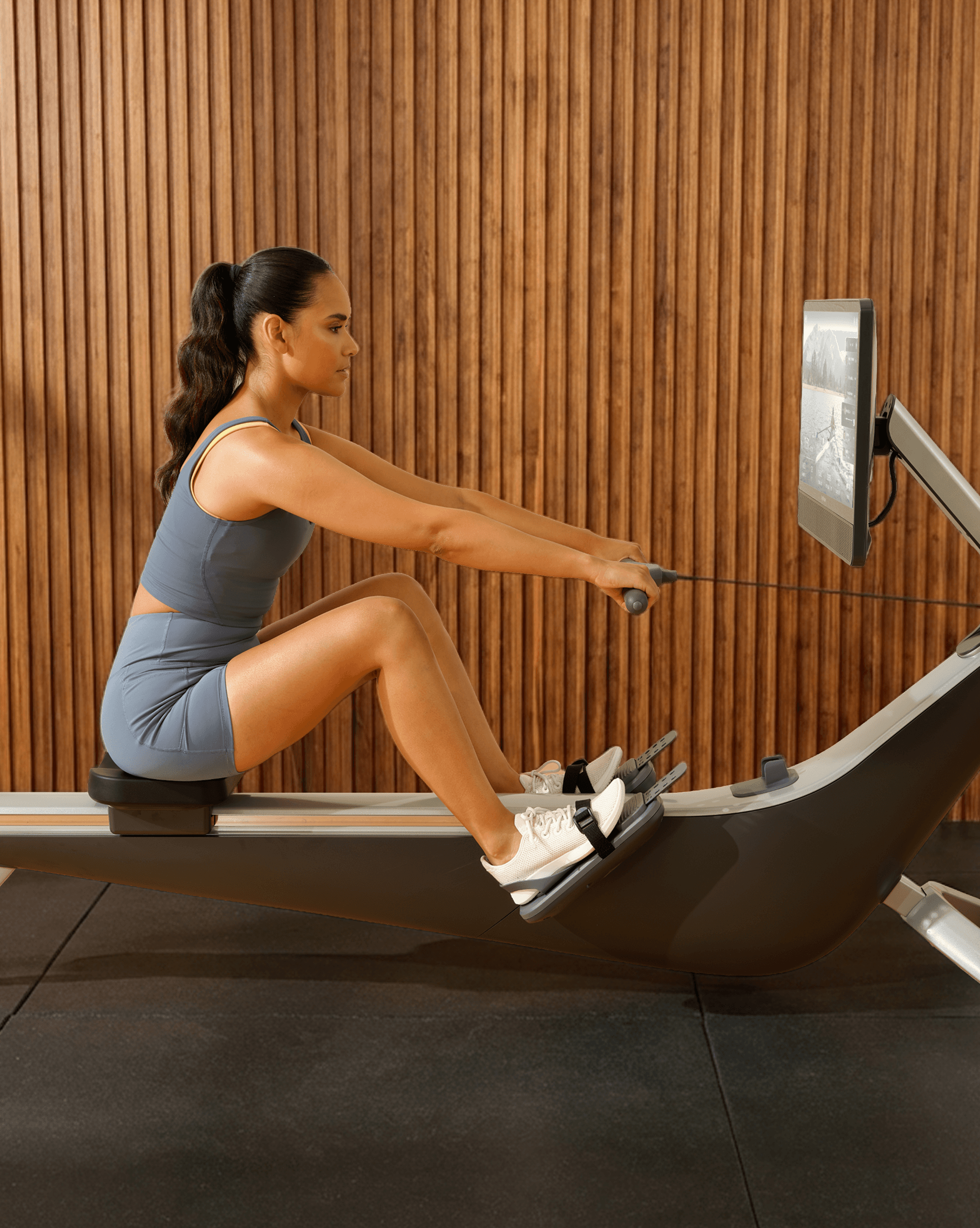 Woman rowing on the Hydrow Arc in a modern home