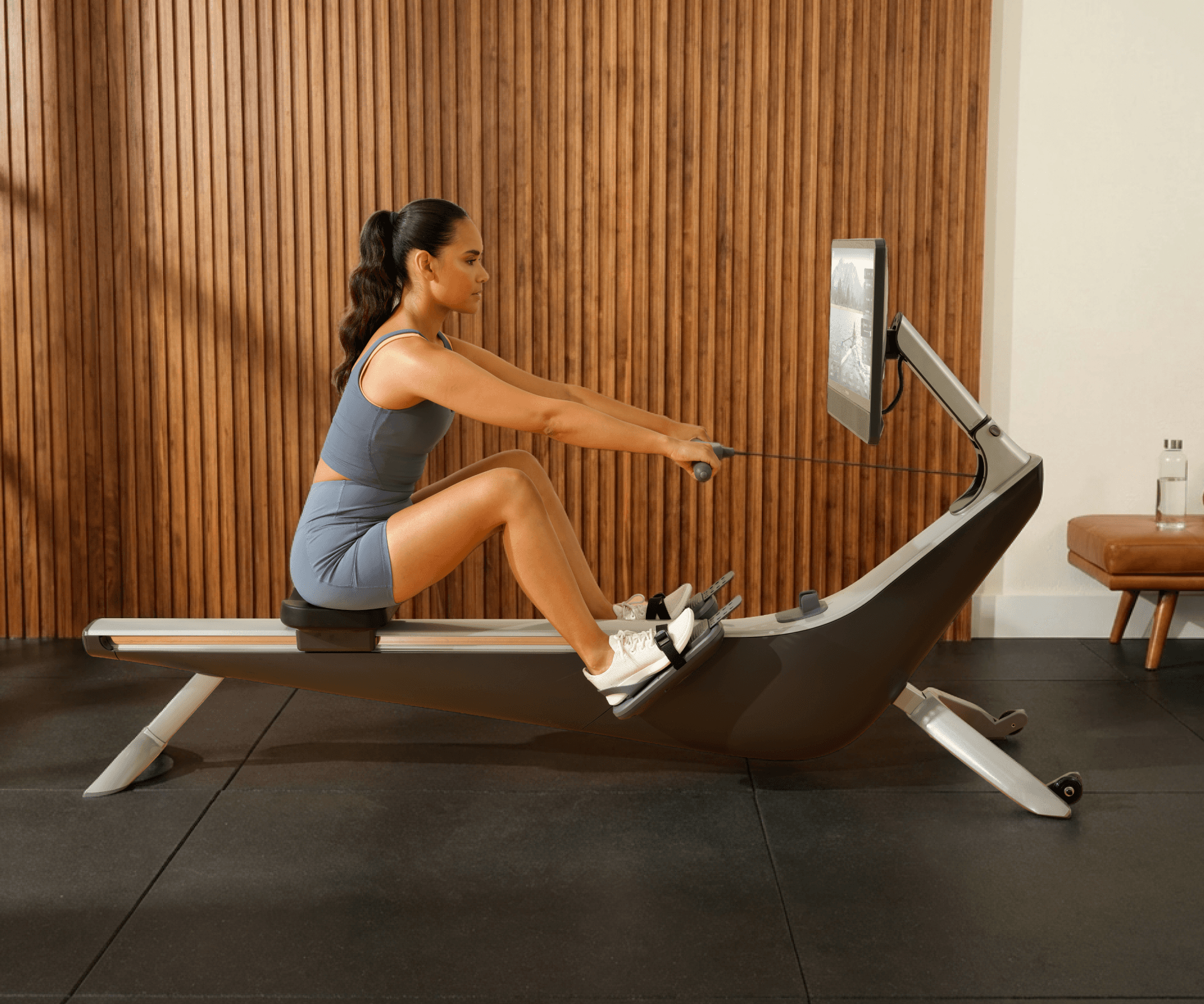 Woman rowing on the Hydrow Arc, engaged in a class on screen.